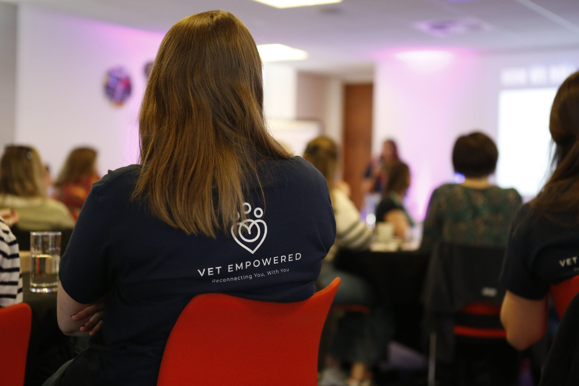 A Vet Empowered member in a branded T-shirt at a live event, surrounded by the community