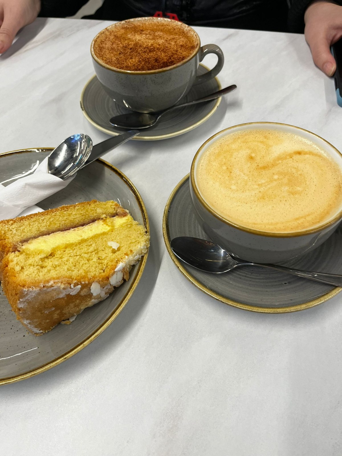 Two coffees and cake on a café table