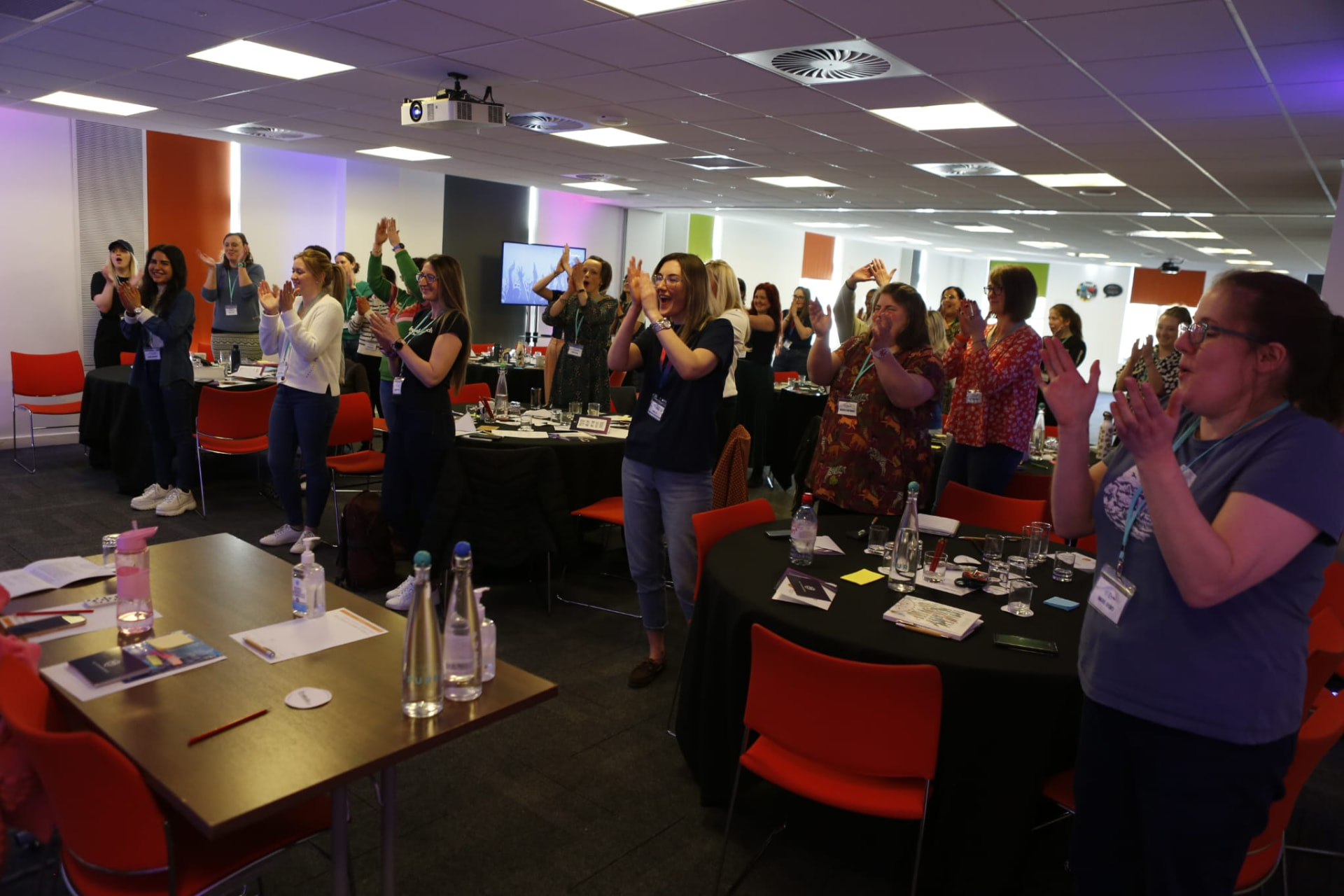 A full room of veterinary professionals on their feet, clapping and cheering