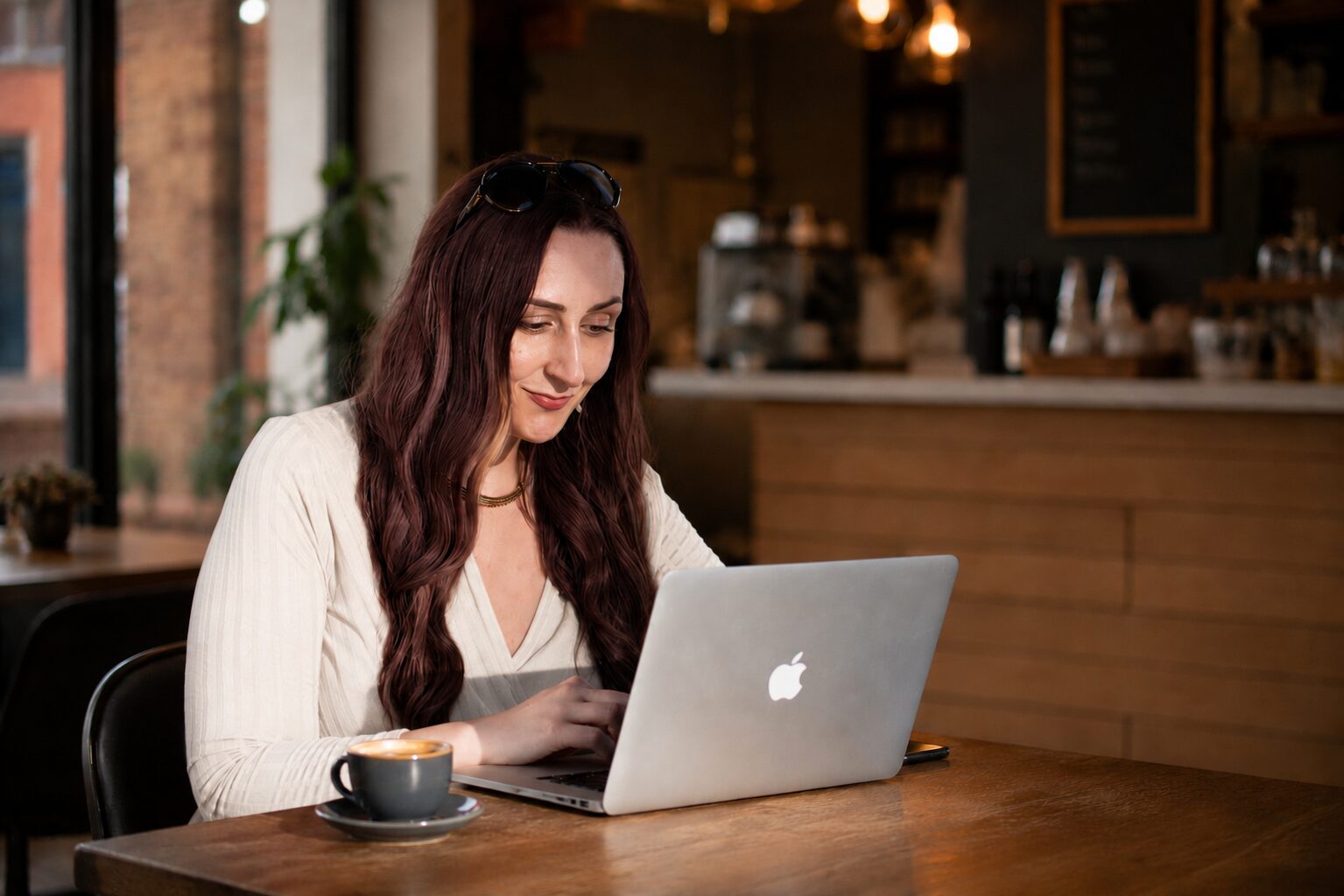 Dr Katie Ford working on a laptop with a coffee in a café
