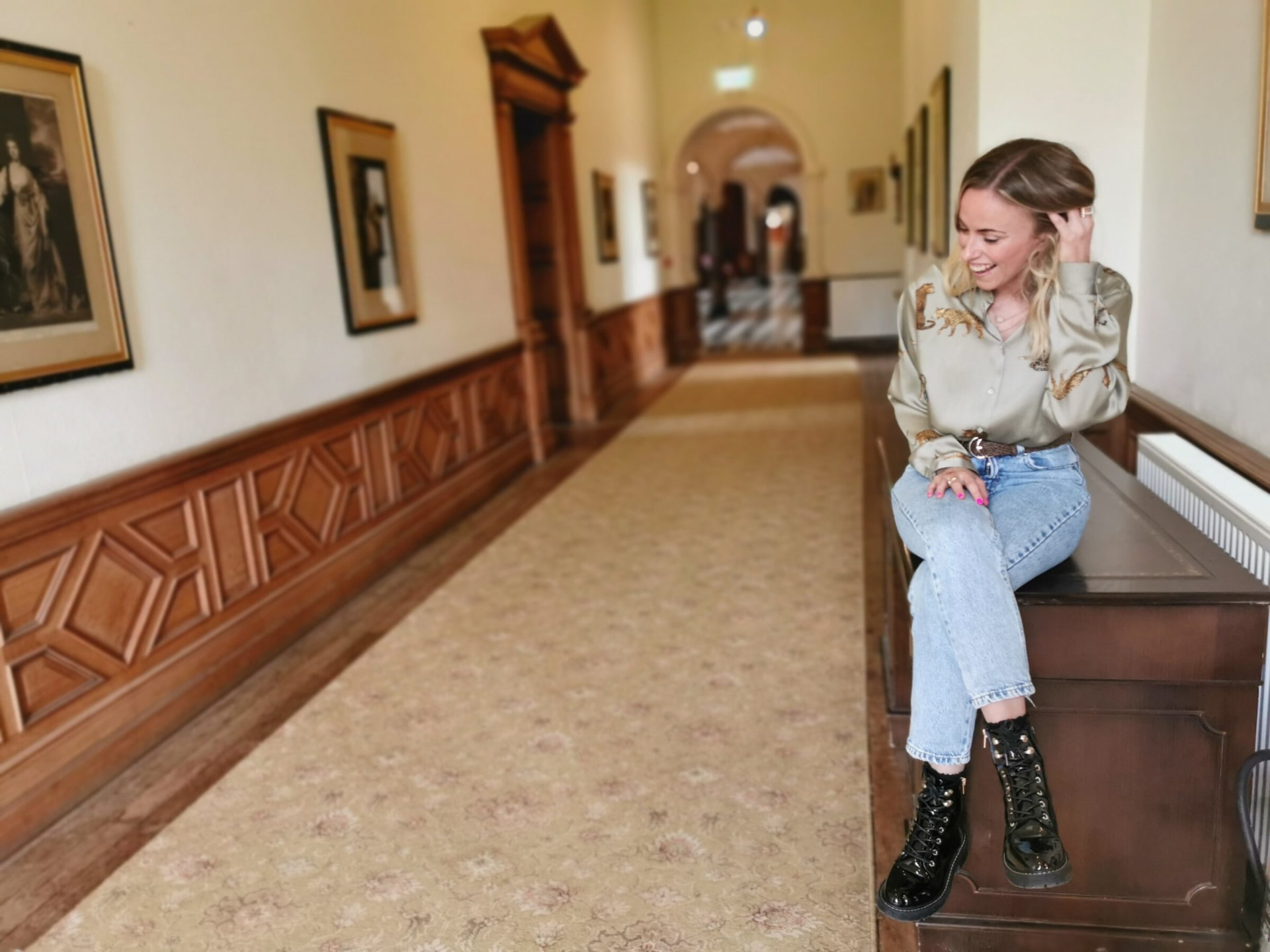 Claire Grigson laughing on a bench in a long corridor