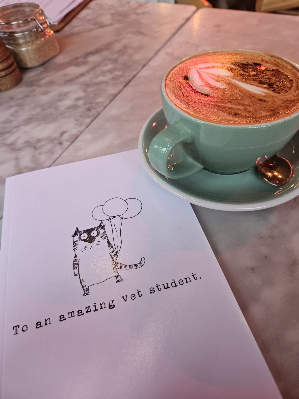 A coffee beside a card reading To an amazing vet student