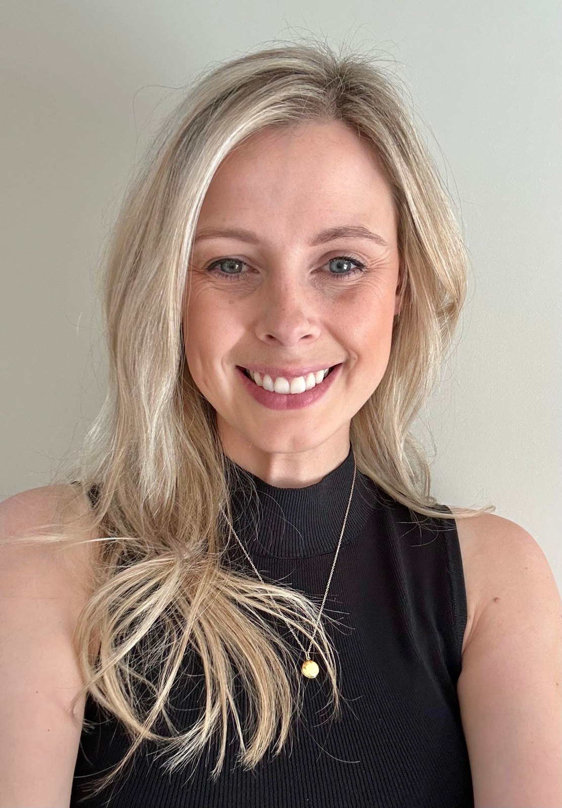 Alex Kendall smiling, with long blonde hair, against a pale wall.