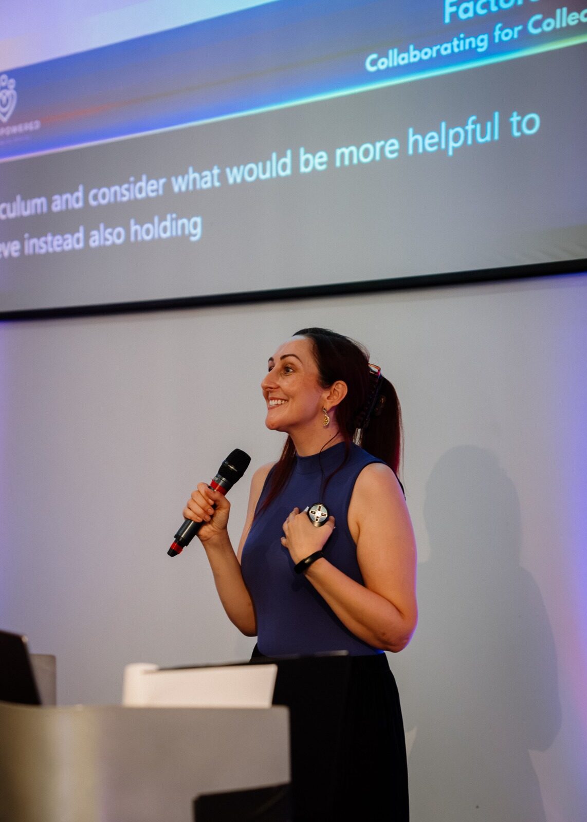 Dr Katie Ford speaking on stage with her hand on her heart