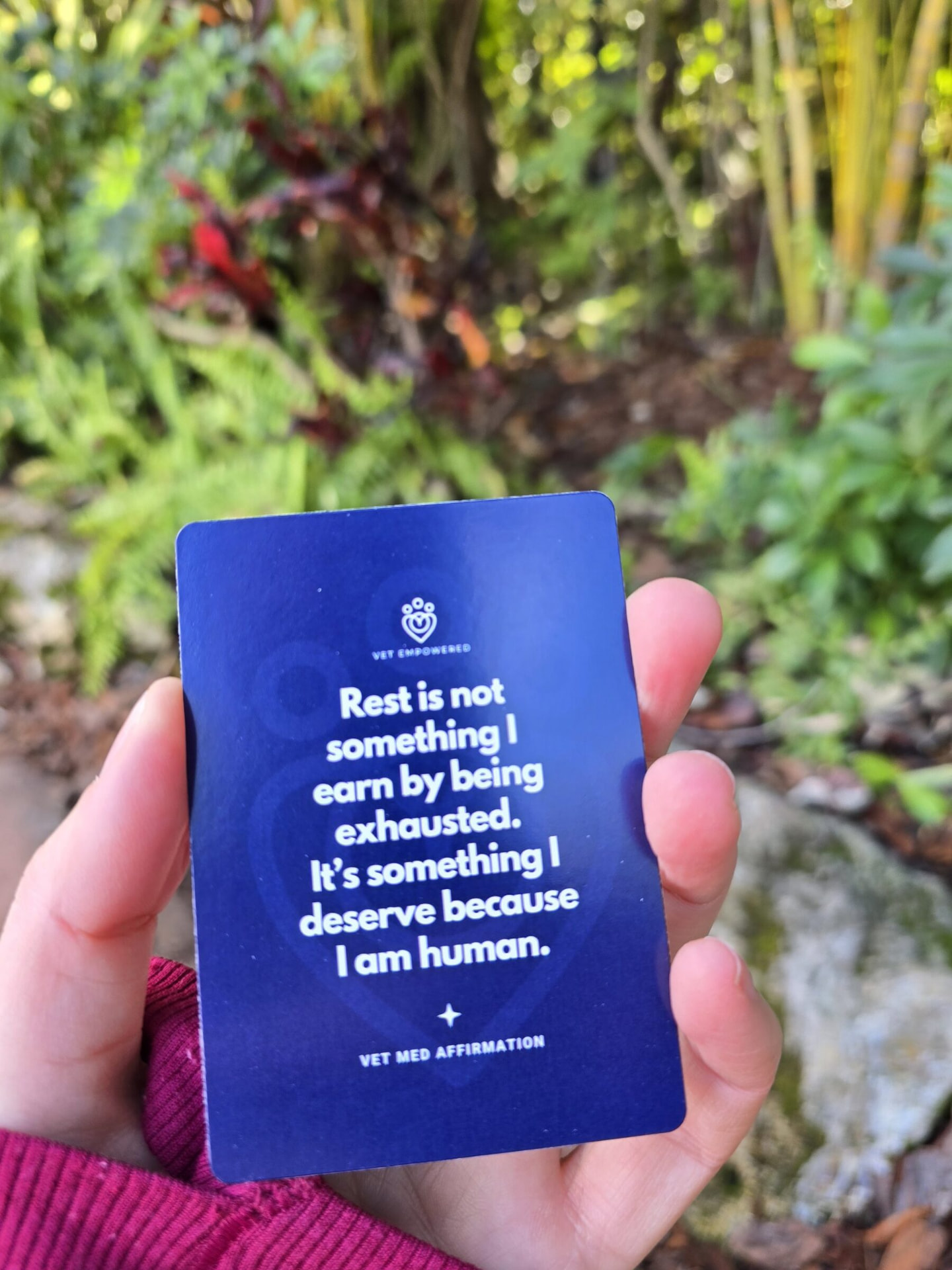 A hand holding a Vet Empowered affirmation card about rest